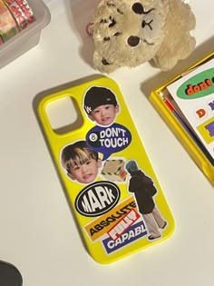 a yellow case with stickers on it next to a teddy bear and other items