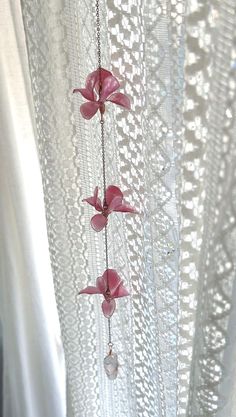 pink flowers hanging from the side of a white curtain