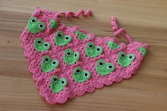 a pink crocheted bag with green eyes on it