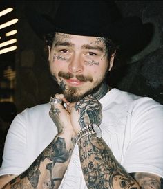 a man with tattoos on his arms and chest posing for the camera while wearing a hat