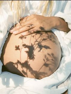 a pregnant woman's shadow cast on her stomach and back, with flowers in the foreground