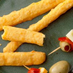 some food is laying out on a green plate with toothpicks and olives