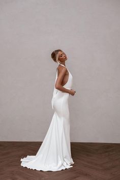 a woman in a white dress standing on a wooden floor with her back to the camera