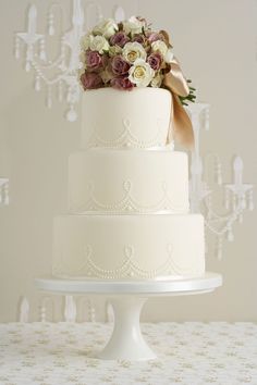 the wedding cake is decorated with white and pink flowers, while the bride and groom are standing next to each other