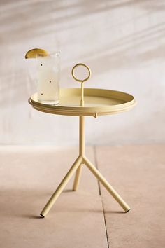 a gold tray with a candle holder on it and a glass in the middle, sitting on a tile floor