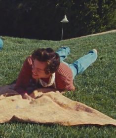 a woman laying on top of a blanket in the grass