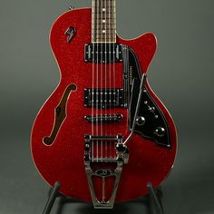 a red electric guitar sitting on top of a stand