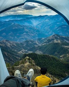 a man sitting in a tent looking out at the mountains and valleys from inside his tent