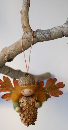 an ornament hanging from a tree branch with leaves and acorns on it