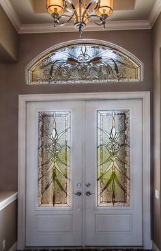 the front door to a home with two glass doors and a chandelier above it