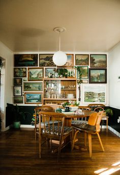 a dining room table with chairs and pictures on the wall in the backround