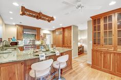 a large kitchen with wooden cabinets and marble counter tops, along with two bar stools