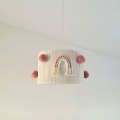 a white lamp hanging from the ceiling with pink pom - poms on it