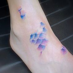 a woman's foot with blue and purple flowers on it, in the middle of her left leg