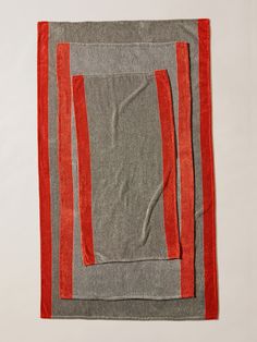 an orange and grey striped towel on a white surface with red trim around the edges