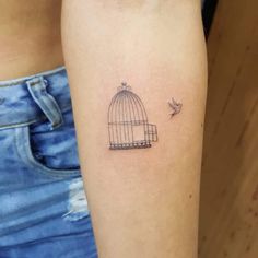 a small bird in a cage tattoo on the arm