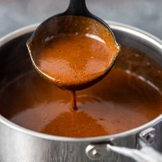 a ladle full of sauce being poured into a pot