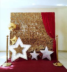 three white stars on a red carpet next to two gold and silver poles with one star in the middle