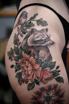 a raccoon tattoo on the side of a woman's thigh with flowers