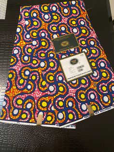 an open notebook with a colorful design on the front and back cover, sitting on a black table