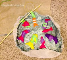 an assortment of colorful toys and knitting needles in a bag on the floor next to some material