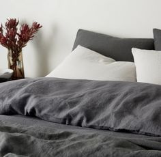 a bed with grey linens and white pillows