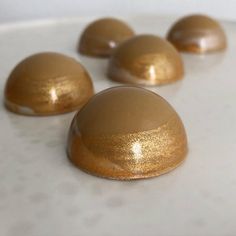 some chocolates are lined up on a white plate with gold flecks around them