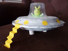 a toy alien in a space ship made out of paper