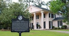 a historical marker in front of a large white house with columns on it's sides