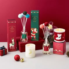 christmas candles and decorations on display against a red background