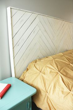 a bed with a yellow comforter and a blue side table in front of it