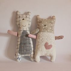 two stuffed animals sitting next to each other on a white surface with pink walls behind them