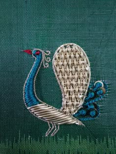 an embroidered peacock on a green background