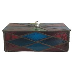 a decorative box with blue, red and green tiles on the lid is shown against a white background