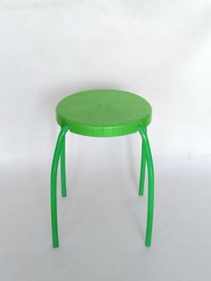 a small green stool sitting on top of a white floor