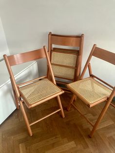 three wooden chairs sitting on top of a hard wood floor