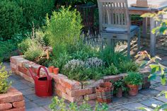 an outdoor garden with brick walls and lots of plants in the center, surrounded by wooden chairs