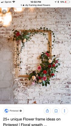 a frame with flowers hanging on the wall next to a brick wall in an old building