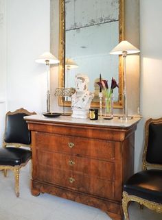 a room with a dresser, mirror and two lamps on the side tables next to each other