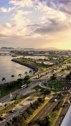 an aerial view of a highway near the ocean with cars driving on it and palm trees in the foreground