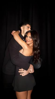 a man and woman hugging each other in the dark