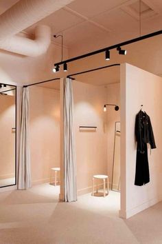 an empty room with clothes hanging on the wall and two mirrors in front of it