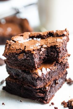 three chocolate brownies stacked on top of each other next to a glass of milk