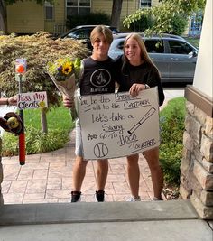 two people holding a sign in front of a building