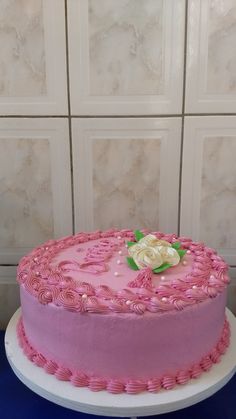 a pink and white cake sitting on top of a blue table next to a wall