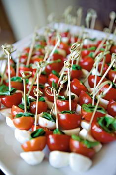 small appetizers with tomatoes and mozzarella are arranged on a platter