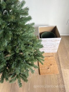 a wooden box sitting on top of a hard wood floor next to a green tree