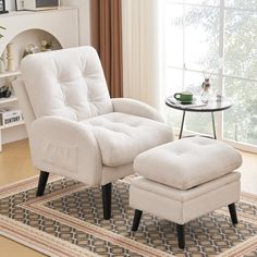 a white chair and ottoman in a living room with a rug on the floor next to a window