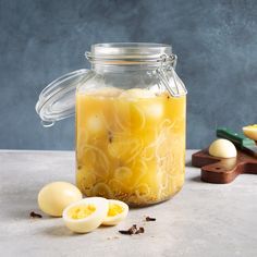 a jar filled with yellow liquid next to eggs