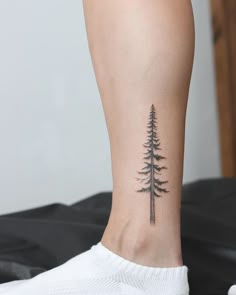 a small pine tree tattoo on the right side of the leg and behind the ankle